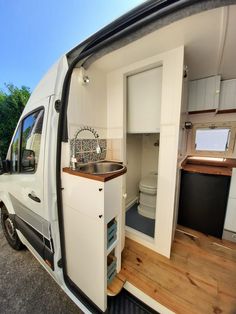 the interior of a camper van with wood flooring and white walls is shown