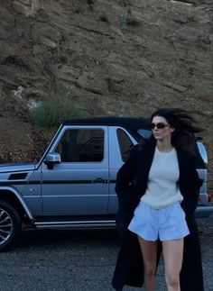 a woman is walking in front of a car