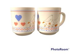 two coffee mugs with hearts and animals painted on the sides, one has a blue heart