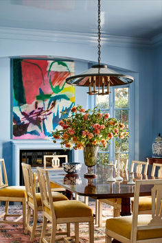 a dining room table with chairs and a vase filled with flowers sitting on top of it