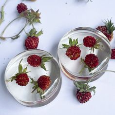 two glass bowls filled with raspberries sitting on top of a table next to each other