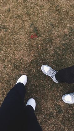 two people standing on top of a grass covered field