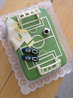 a cake that looks like a soccer field with scissors and ball in it on a doily