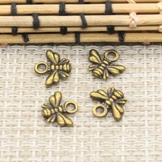 brass plated metal flower charms with black cord on bamboo mat next to bamboo sticks