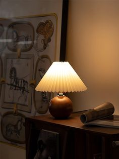 a lamp sitting on top of a wooden table next to a wall with pictures behind it