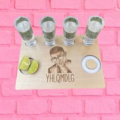 four shot glasses sitting on top of a wooden tray with the word yhlomdlg