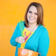 a woman holding a whisk and mixing bowl in front of an orange wall