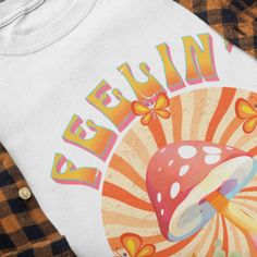 Channel your inner hippie and add a touch of free-spirited style to your wardrobe with our Feelin' Groovy Tee Shirt. This retro-inspired design captures the essence of the 60s and 70s, combining bold, vibrant mushrooms with a groove-themed typography. Made from premium quality fabric, this tee offers superior comfort and long-lasting wear. Whether you're attending a music festival, looking for a unique gift for a fellow flower child, or just want to express your love for all things groovy, this tee is the perfect choice. Embrace the bohemian lifestyle and spread positivity wherever you go with this groovy shirt. Designed on www.kittl.com because they are awesome. .: 100% ring-spun cotton (fiber content may vary for different colors) .: Light fabric (4.5 oz/yd² (153 g/m .: Eurofit .: Tear-a Cheap Retro T-shirt For Music Festival, Groovy T Shirt, 60's Party, Decades Party, Groovy Tees, 60s Party, Groovy Shirt, Feelin Groovy, Festival Shirt