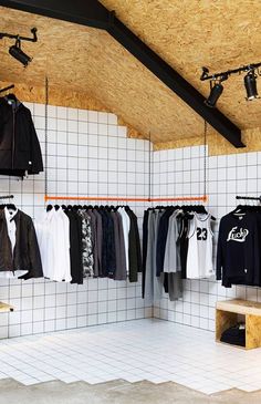 clothes are hanging on racks in a room with white tile walls and wooden ceilinging