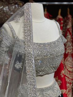 Iced cube sliver lehenga with frosted crystal embroidery teamed with a spaghetti strap blouse with crystal embroidery and net dupatta. Fabric: Net Custom designed according to client measurements and color preference. Production and delivery time is 120 days! Sliver Lehenga, Glamorous Silver Choli With Mirror Work, Glamorous Silver Choli With Zari Work, Festive Silver Glamorous Choli, Glamorous Embellished Silver Lehenga, Embellished Silver Saree Set, Designer Embellished Silver Lehenga, Glamorous Embellished Silver Choli, Glamorous Silver Choli For Reception