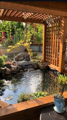 a small pond in the middle of a patio with a wooden pergolan over it