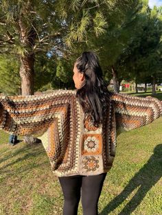 a woman standing in the grass wearing a crocheted shawl and leggings