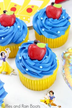 some cupcakes with blue frosting and an apple on top are sitting on a table