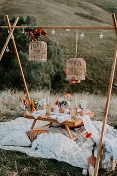 an outdoor picnic setting with flowers, candles and birdcage hanging from the ceiling