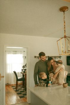 a man, woman and child are standing at the kitchen counter with their arms around each other