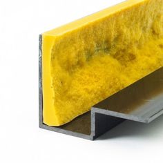 a piece of yellow and gray colored material on a white surface with metal edge, closeup