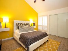 a bedroom with yellow walls and white furniture