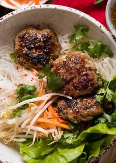 two meat patties in a white bowl with noodles and lettuce on the side