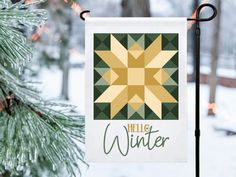 a banner hanging from a pole in front of a snow covered forest with pine trees