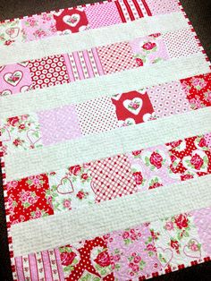 a pink and red quilted table runner with hearts on the border, along with matching fabric