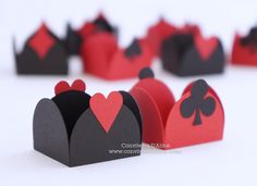 several paper crowns with hearts and spades on the top one has a red heart in the middle