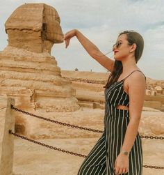 a woman pointing at the sphinx in front of an ancient egyptian pyramid with chains around her