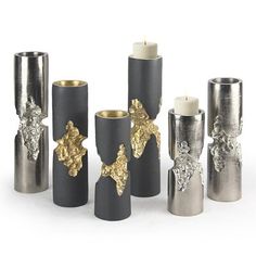 a group of silver and gold candles sitting next to each other on a white surface