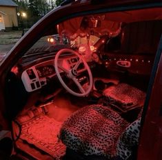 the interior of a car with leopard print cushions and red lights in the dash light