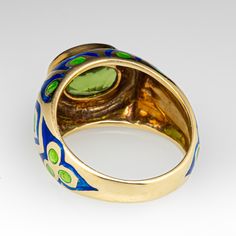 This artful ring is centered with one (1) bezel set oval cut peridot. The domed ring design features ornate green and blue enamel. The ring measures 12.0mm at the top, and rises 6.5mm above the finger, tapering to 3.7mm wide and 1.1mm thick at the base of the shank. The ring now and always fits a size 7, as we are not offering sizing due to the enamel. Green Enamel Open Ring, Oval Yellow Gold Cabochon Enamel Ring, Green Enamel Fine Jewelry Ring, Yellow Gold Enamel Cabochon Ring, Luxury Green Enamel Ring, Antique Engagement Rings Sapphire, Estate Jewelry Rings, Peridot Ring, European Cut Diamonds