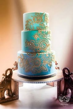 there is a three layer cake with gold designs on the top and blue frosting on the bottom