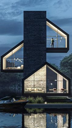 two people are standing in the windows of a modern house on water's edge