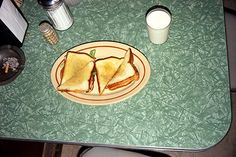 a plate with two sandwiches on it next to a glass of milk