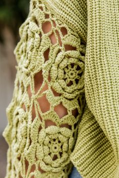 a woman is wearing a green sweater with crochet