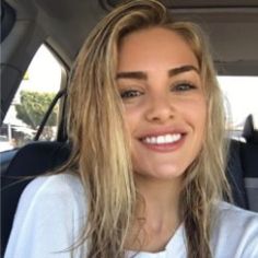 a woman with long hair sitting in the back seat of a car smiling at the camera