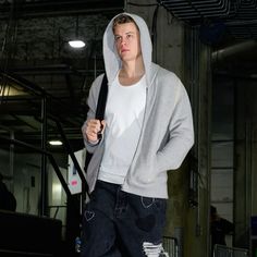 a young man in a white hoodie and ripped jeans