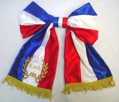 a red, white and blue scarf with gold trimmings sits on a table