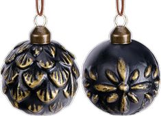 two black and gold ornaments are hanging from metal hooks, one with an ornate design on it