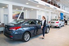 a woman standing next to a car in a showroom