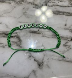 a green beaded bracelet with the word boston on it sitting on a marble surface