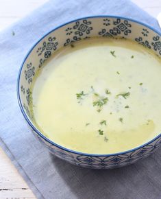 a blue and white bowl filled with soup on top of a napkin next to a spoon