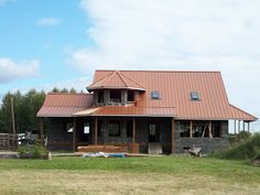 a large brown house sitting on top of a lush green field