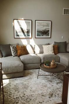 a living room with two pictures on the wall and a large sectional couch in front of it