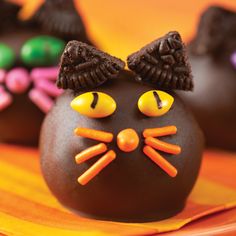 three chocolate cats are decorated with candy sticks