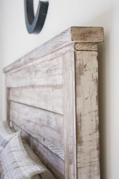 a bed with a wooden headboard and two pillows on top of it, next to a wall mounted clock