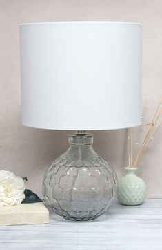 a table lamp sitting on top of a wooden table next to a book and flowers