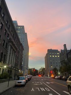 cars are parked on the street in front of tall buildings at sunset or sunrise time