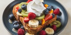 a blue plate topped with french toast covered in whipped cream and fresh fruit on top