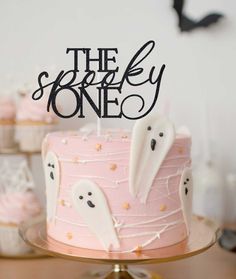 a pink cake topped with white frosting and ghost decorations