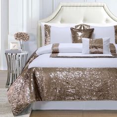 a bed with gold sequins and pillows on top of it in a room