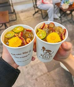 two people holding up cups filled with food